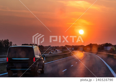Scenic highway at sunset with minivan and cars and trucks driving through a dirty windshield. Concept of travel, transportation, freedom and the beauty of evening skies on the open road. Copy space Scenic highway at sunset with minivan and cars and trucks driving through a dirty windshield. Concept of travel, transportation, freedom and the beauty of evening skies on the open road. Copy space 140328790