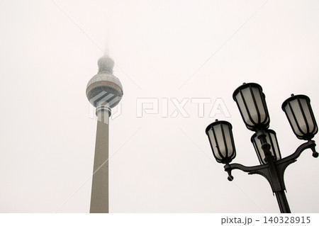 Minimalist Berlin skyline view with Berlin TV tower disappearing into fog. Foggy Fernsehturm in Berlin, Germany. Vntage street lamps in the foreground. Cloudy sky on background. Copy space Minimalist Berlin skyline view with Berlin TV tower disappearing into fog. Foggy Fernsehturm in Berlin, Germany. Vntage street lamps in the foreground. Cloudy sky on background. Copy space 140328915