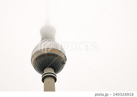 Berlin TV tower in dense fog, iconic Alexanderplatz landmark disappearing into mist. Foggy Fernsehturm in Berlin, Germany. Cloudy sky on background. Copy space 140328918