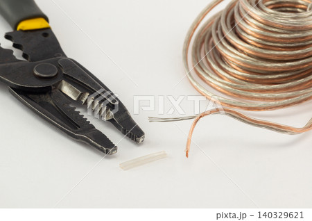 Wire stripper tool and transparent copper speaker cable close-up Wire stripper tool and transparent copper speaker cable close-up 140329621