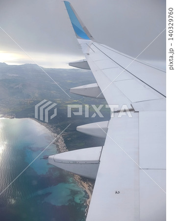 View from the airplane window of the wing, sea and coast on a sunny day View from the airplane window of the wing, sea and coast on a sunny day 140329760