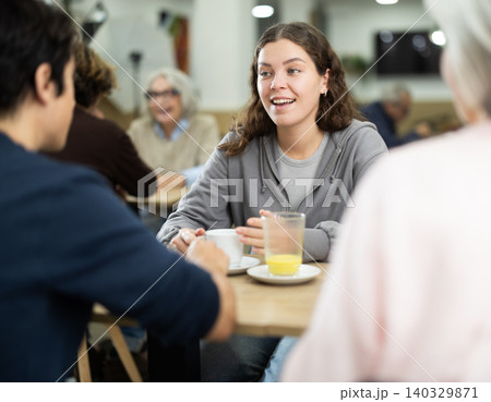 Positive young girl meeting and chatting with family in cozy cafeteria 140329871