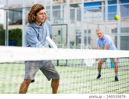 Focused adult man playing paddle tennis outdoors Focused adult man playing paddle tennis outdoors 140329876