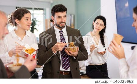 Group of friendly young office workers different ages standing and eating fast food at modern office canteen Group of friendly young office workers different ages standing and eating fast food at modern office canteen 140329962