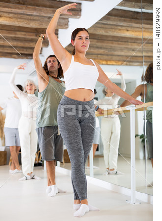 Women and men training in ballet class with other dancers in studio Women and men training in ballet class with other dancers in studio 140329999