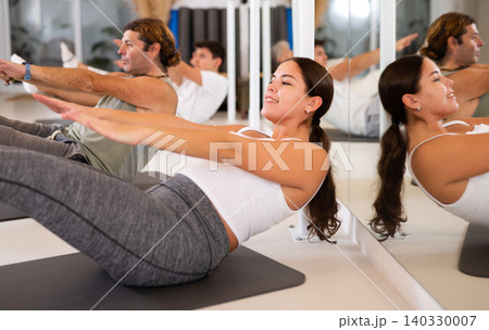 People different ages performing set of pilates exercises in fitness studio 140330007