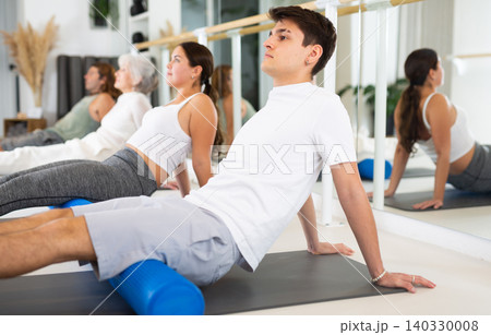 Sports people practicing pilates with rolled mats at group class in yoga studio Sports people practicing pilates with rolled mats at group class in yoga studio 140330008