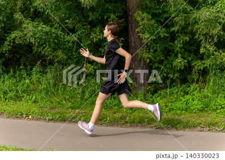 Young woman jogging on a park path 140330023