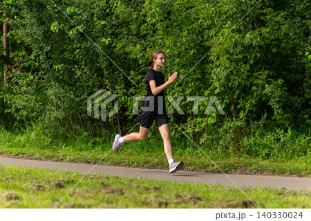Young woman running on a park path Young woman running on a park path 140330024