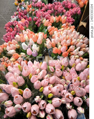 Armfuls of multi-colored tulips in packaging, ready for sale, at a flower market or in a store. Armfuls of multi-colored tulips in packaging, ready for sale, at a flower market or in a store. 140330104