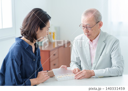 娘から薬の説明を受ける高齢者の男性 娘から薬の説明を受ける高齢者の男性 140331459