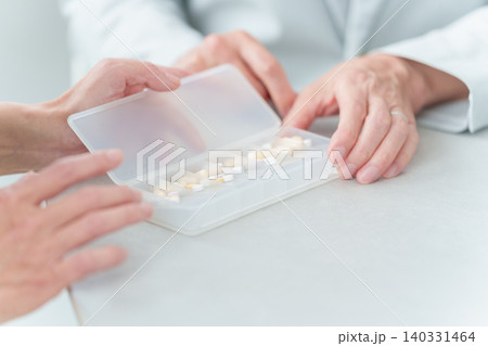 娘から薬の説明を受ける高齢者の男性 娘から薬の説明を受ける高齢者の男性 140331464