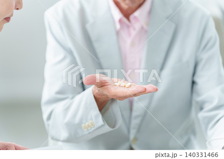 娘から薬の説明を受ける高齢者の男性 娘から薬の説明を受ける高齢者の男性 140331466
