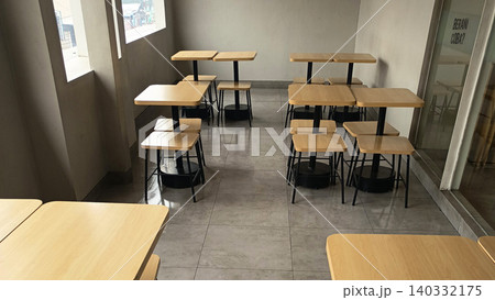 Photo of a modern cafe interior featuring an arrangement of wooden tables and chairs with a minimalist design. 140332175