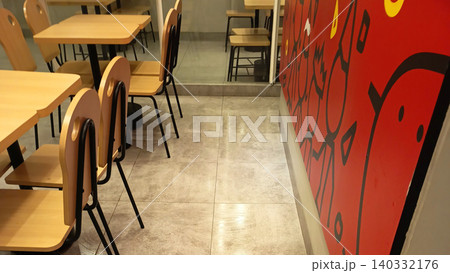 Photo of a modern cafe interior featuring an arrangement of wooden tables and chairs with a minimalist design. Photo of a modern cafe interior featuring an arrangement of wooden tables and chairs with a minimalist design. 140332176