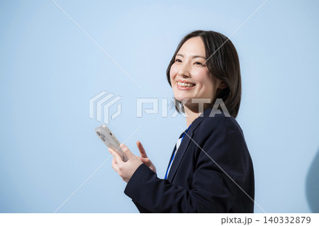 水色背景でスマートフォンで検索、探す、問合せ、コンタクト等確認するビジネスウーマン 水色背景でスマートフォンで検索、探す、問合せ、コンタクト等確認するビジネスウーマン 140332879