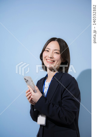 水色背景でスマートフォンで検索、探す、問合せ、コンタクト等確認するビジネスウーマン カメラ目線 水色背景でスマートフォンで検索、探す、問合せ、コンタクト等確認するビジネスウーマン カメラ目線 140332882