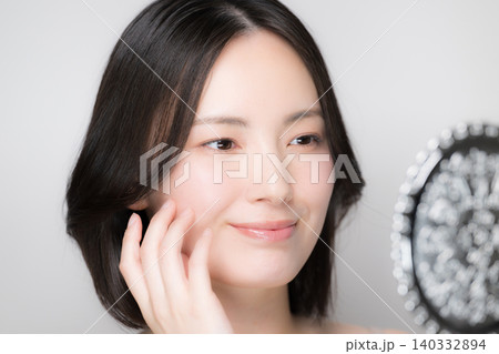 手鏡を見ながら肌の状態を手で触れる確認する若い女性とスキンケアクローズアップ 手鏡を見ながら肌の状態を手で触れる確認する若い女性とスキンケアクローズアップ 140332894