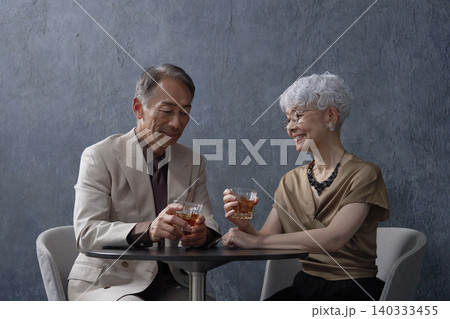 ウィスキーを飲むシニアの夫婦 黒背景 ウィスキーを飲むシニアの夫婦 黒背景 140333455