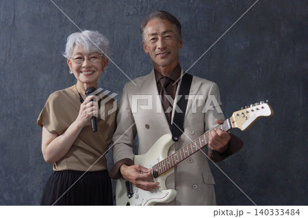 シニアのミュージシャン　男性のギタリストと女性のボーカル　黒背景　カメラ目線 140333484