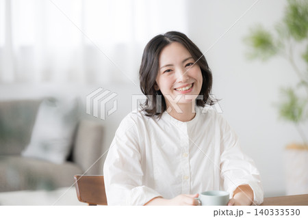 自宅でリラックスしながら笑顔を見せる若い女性や主婦のライフスタイル カメラ目線 自宅でリラックスしながら笑顔を見せる若い女性や主婦のライフスタイル カメラ目線 140333530