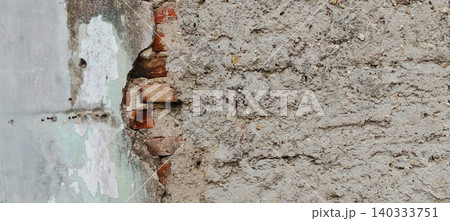 Damaged plaster walls with visible brick texture and weathered concrete surfaces 140333751