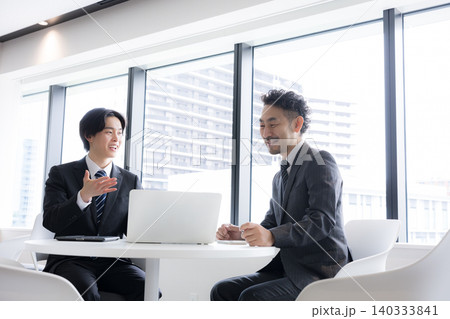 ノートパソコンを使いながら打ち合わせを行うビジネスマン二人 若手が提案する明るい営業シーン ノートパソコンを使いながら打ち合わせを行うビジネスマン二人 若手が提案する明るい営業シーン 140333841