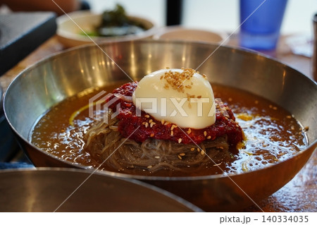 Traditional Korean cold noodle dish naengmyeon served in a brass bowl Traditional Korean cold noodle dish naengmyeon served in a brass bowl 140334035