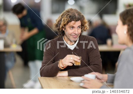 adult is sitting at a table in a cafe and talking adult is sitting at a table in a cafe and talking 140334072