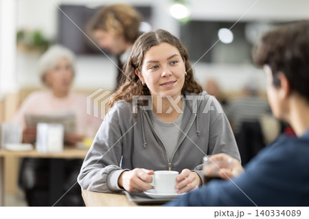 Young chatting at coffee shop table Young chatting at coffee shop table 140334089