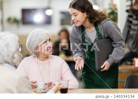 woman waiter takes an order from elderly women in a cafe woman waiter takes an order from elderly women in a cafe 140334134