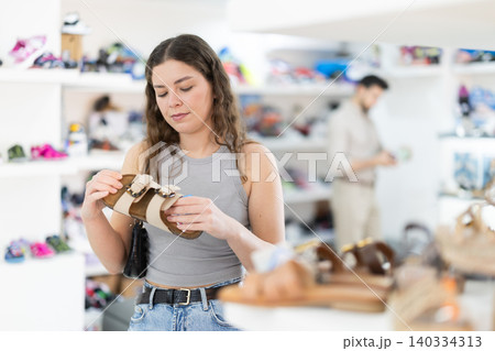 Young woman choosing sandals at footwear store 140334313