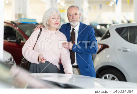 Elderly is standing in a car dealership Elderly is standing in a car dealership 140334384