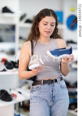 Woman shopper in shoe store is looking at summer sneakers 140334711