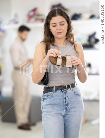 Young woman choosing sandals at footwear store 140335150