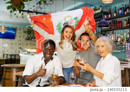 Cheering group of sport fans rejoicing team victory with glasses of beer in bar, watching match, man showing thumb up 140335213
