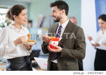 Man and woman office workers resting on break together eating and talking Man and woman office workers resting on break together eating and talking 140335467