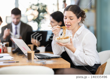 Young female companys employees eat instant noodles, lunch time during break for staff Young female companys employees eat instant noodles, lunch time during break for staff 140335496
