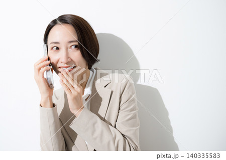 スマートフォンでコッソリ内緒で話す、口コミやレビューのスーツのビジネス女性のクローズアップ 140335583
