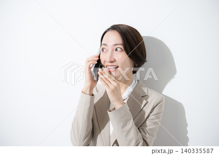 スマートフォンでコッソリ内緒で話す、口コミやレビューのスーツのビジネス女性のクローズアップ 140335587