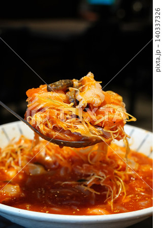 Close-up of traditional Korean cold seafood dish served with a large spoon over a bowl Close-up of traditional Korean cold seafood dish served with a large spoon over a bowl 140337326