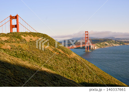 Sunlit Marin Headlands framing Golden Gate Bridge over blue bay Sunlit Marin Headlands framing Golden Gate Bridge over blue bay 140337661