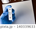 Gloved hand holding a negative Ebola antigen rapid test kit cassette 140339633