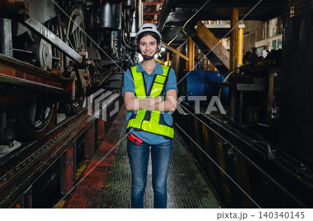 Young worker stands confidently in industrial plant corridor Young worker stands confidently in industrial plant corridor 140340145