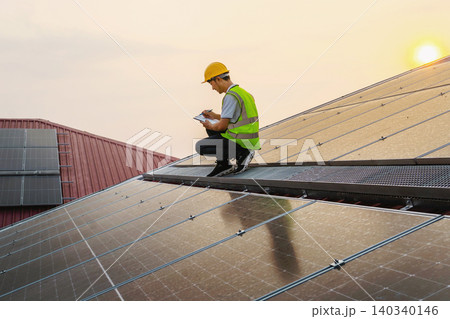 Solar technician inspects panels with notebook Solar technician inspects panels with notebook 140340146