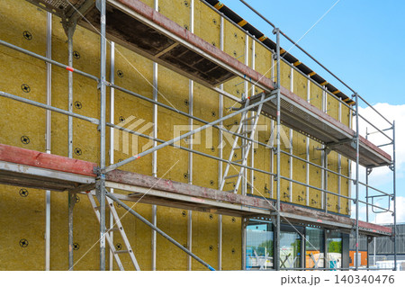 Mineral wool facade insulation and scaffolding on modern commercial building during construction Mineral wool facade insulation and scaffolding on modern commercial building during construction 140340476