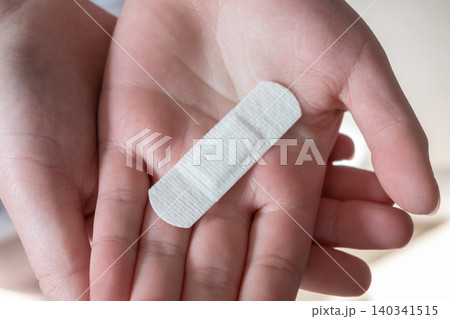 Young woman with medical adhesive plaster on the hand after vaccination. Fabric white bandage like first help for wound on the damage skin. Young woman with medical adhesive plaster on the hand after vaccination. Fabric white bandage like first help for wound on the damage skin. 140341515
