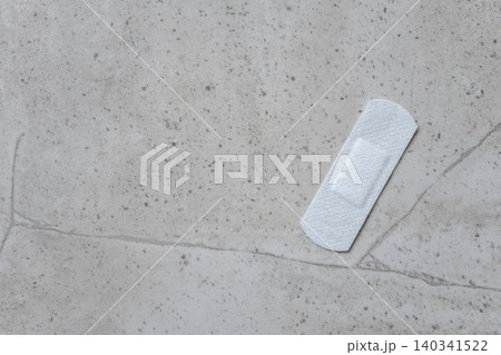 Medical adhesive plaster after vaccination on the stone background. Fabric white bandage like first help for wound on the damage skin. Space for text. Medical adhesive plaster after vaccination on the stone background. Fabric white bandage like first help for wound on the damage skin. Space for text. 140341522
