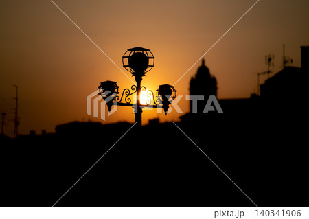 Ornate street lamp silhouette against golden sunset sky in Caltagirone, Sicily Ornate street lamp silhouette against golden sunset sky in Caltagirone, Sicily 140341906