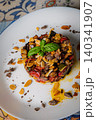 Traditional Sicilian roasted vegetable dish with toasted almonds and fresh basil on white plate 140341907